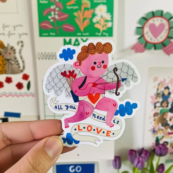 Daria-Solak-Hand -hält-Aufkleber--handgemalt- kleiner -Putti-mit- text-all-you-need-is-love
