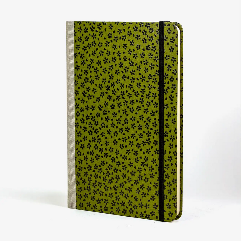 notizbuch-liniert-format-a5-144-seiten-bezogen-mit-Lackpapier-kleine-schwarze-blueten-auf-gruen-cover-seitlich-vorn